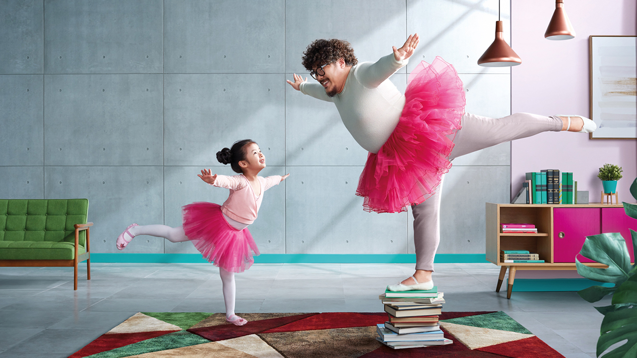 Dad and his daughter are dressing up in ballet costumes and performing at home; image used for HSBC FirstSave Insurance Plan.