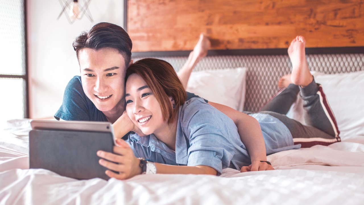 A Couple is looking at tablet in bedroom; image used for building your wealth.