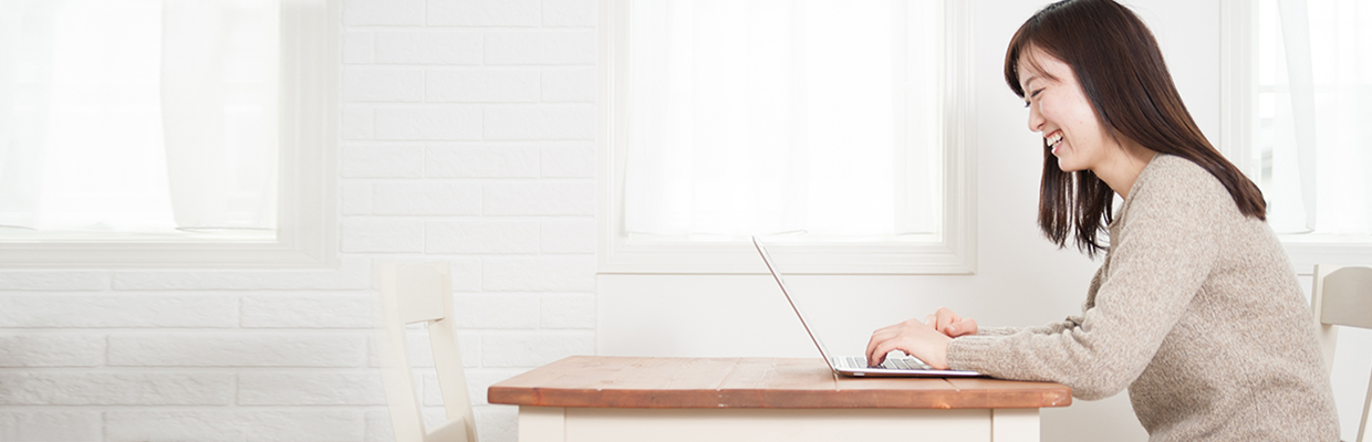 A smiling woman looking at her laptop; image used for the HSBC’s e-Cheque services page.	