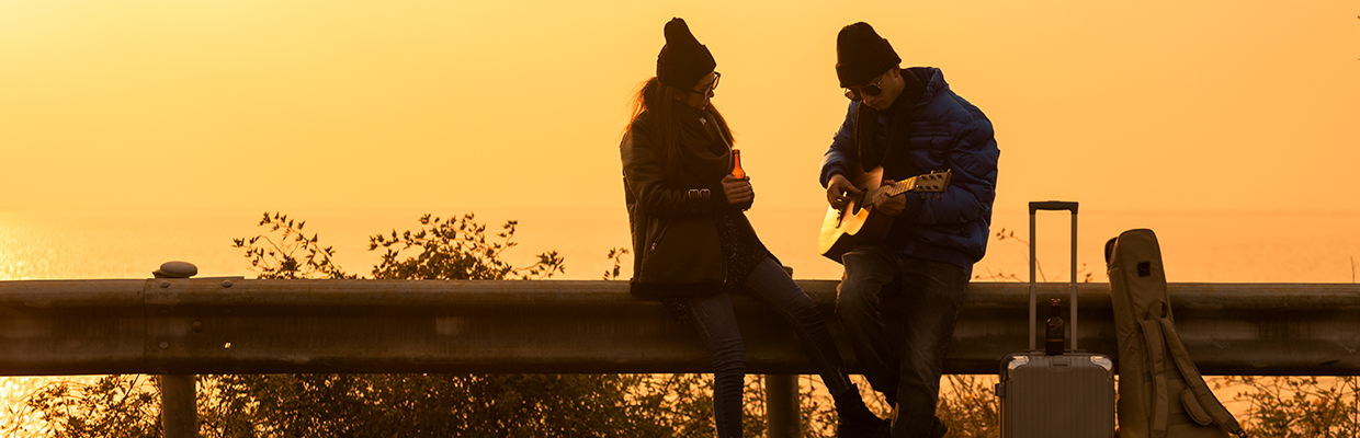 一对夫妇在夕阳下欣赏音乐；图片使用于汇丰银联双币信用卡。