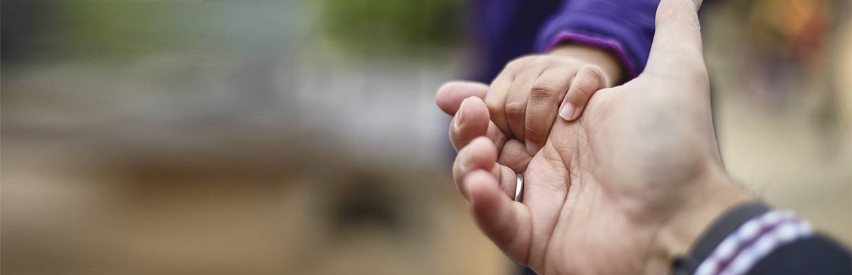 一个孩子握着他父亲的手；图片使用于协助及支援