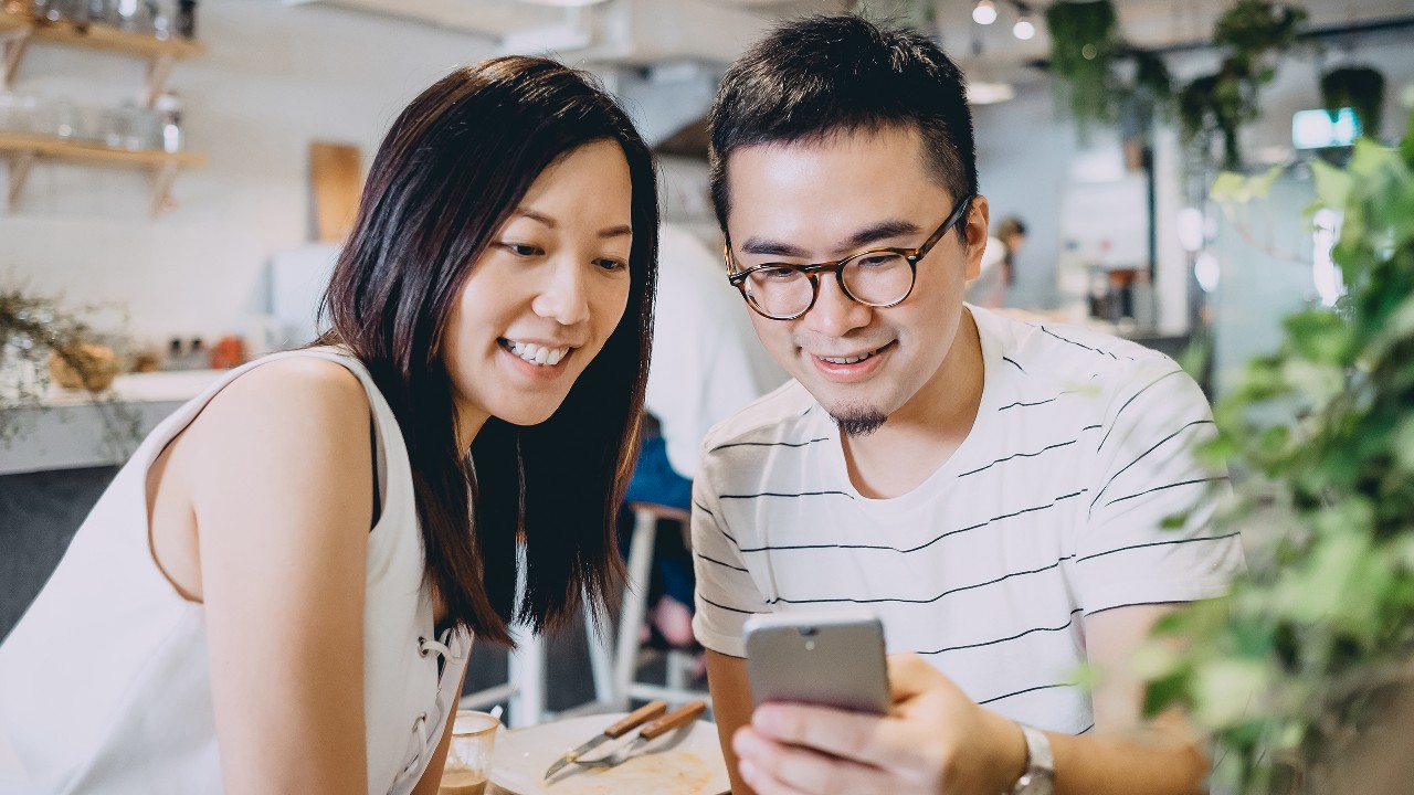 Couple checking phone; image used for HSBC Red Hot Rewards.