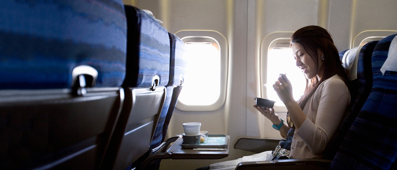 一个女人正在坐飞机。图像用于汇丰飞行优惠计划。