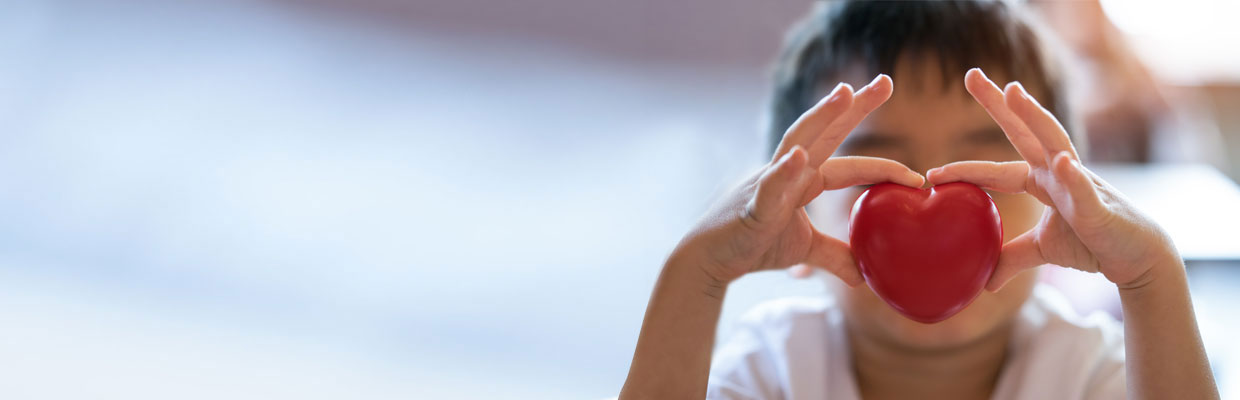 A child holding a red heart; image used for Banking support for customers with health issues.