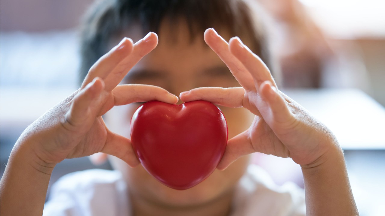 A child holding a red heart; image used for Banking support for customers with health issues.