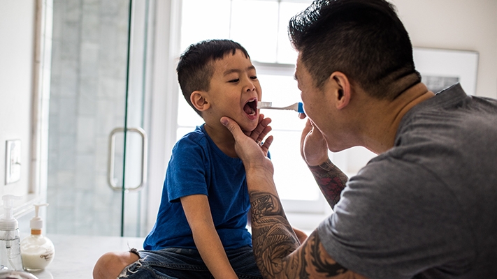 父親正在幫他的兒子刷牙；圖片使用於滙豐醫療保險頁面。