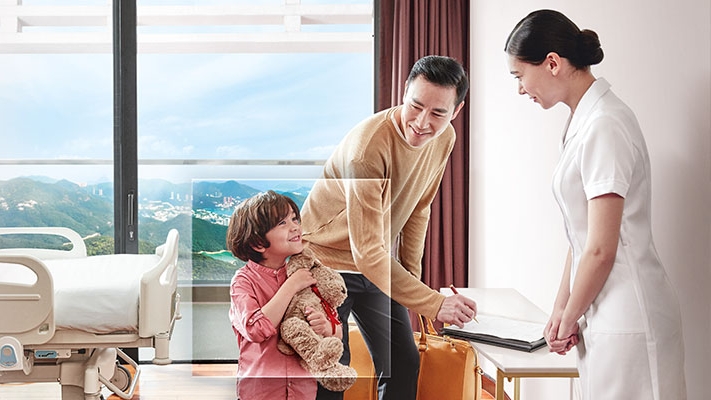 A father is helping his son for signing in hospital ; image used for HSBC FirstCare Plus Insurance.