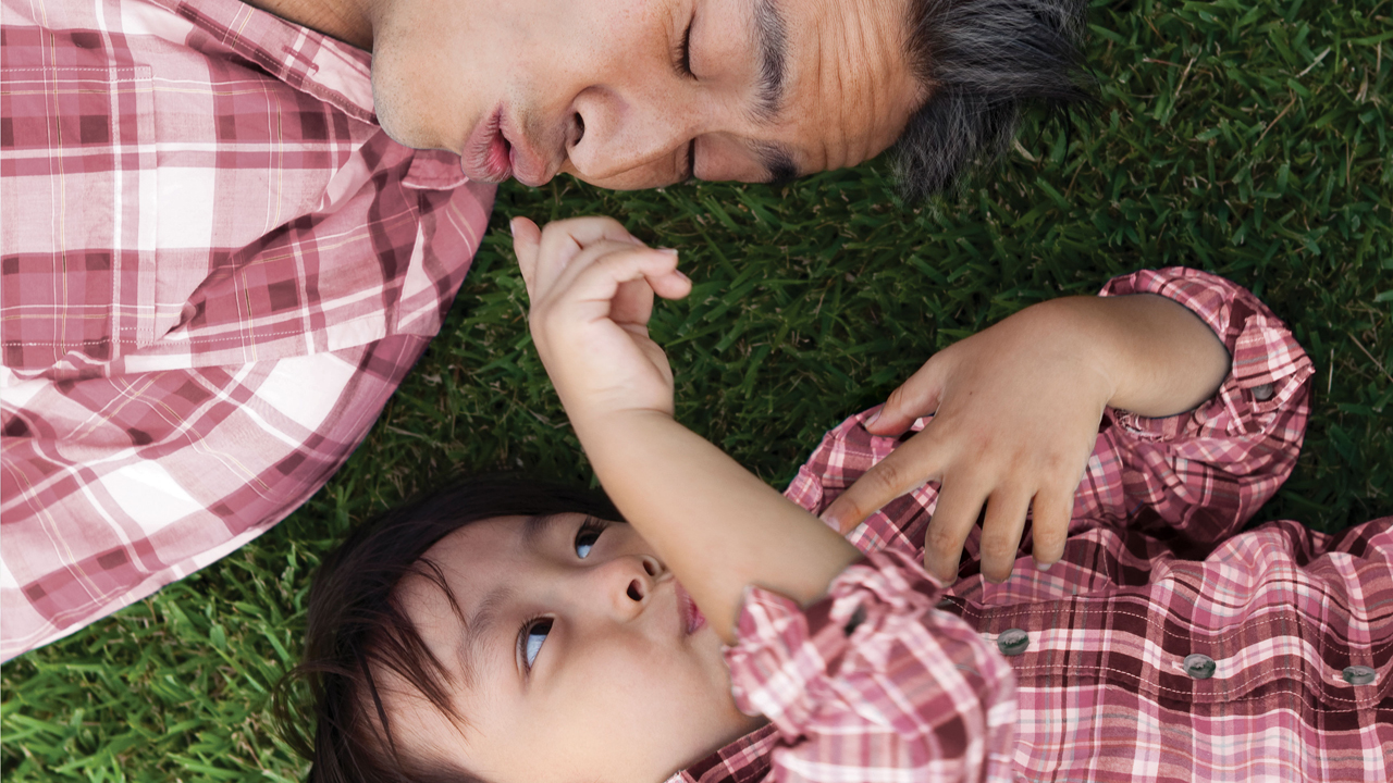 爸爸与儿子在草地上；图片使用于骏富保障万用寿险计划页面。