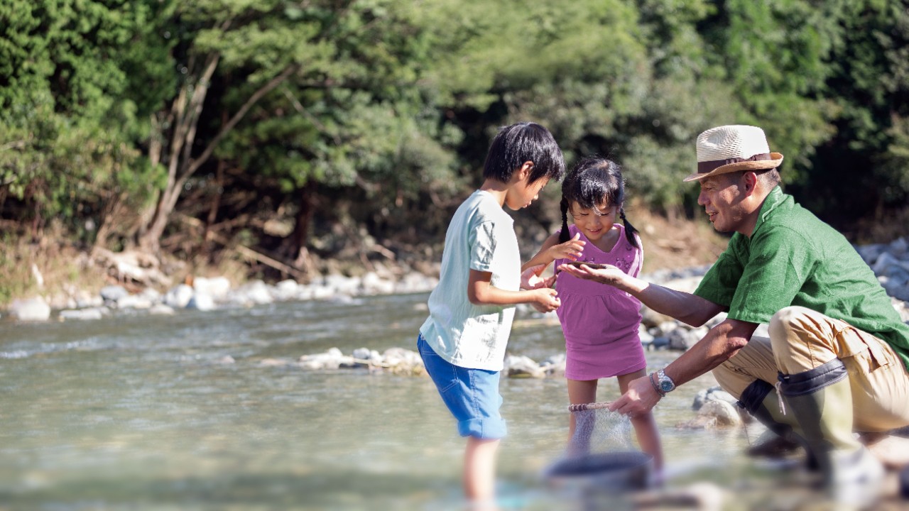 Kids and father near river; image used for HSBC WholeLife Protection Plan.