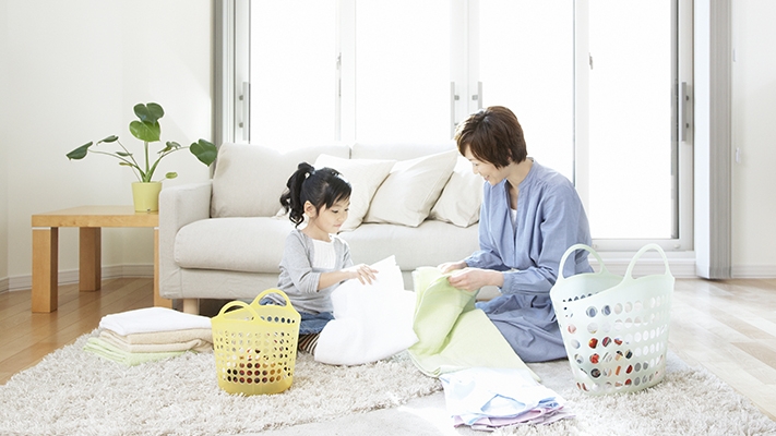 Little daughter helping mother folding family clothing; image used for HSBC Helper Insurance.