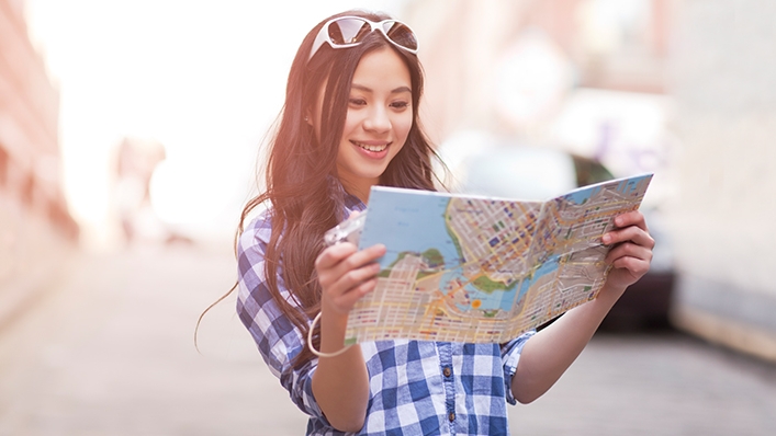 一個女子在看地圖；圖片使用於滙豐旅遊萬全保頁面。