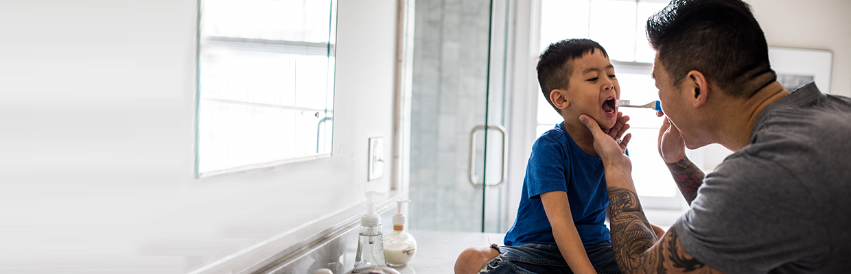 A father helps his son brushing his teeth; image used for HSBC Medical Insurance. 