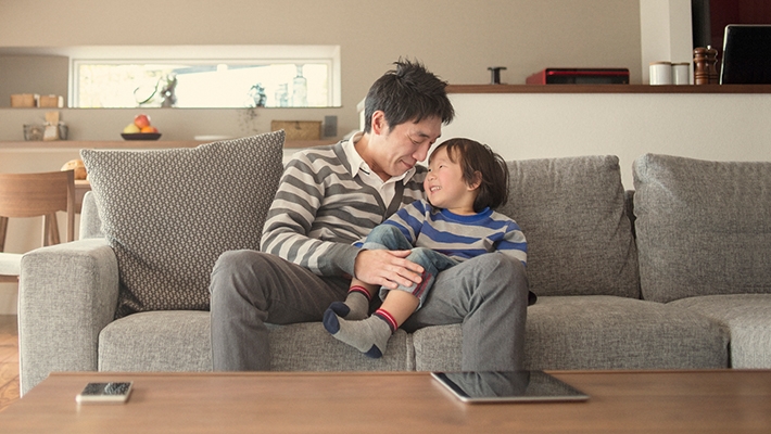 Father is hugging his son in sofa; image used for HSBC Term Protector.