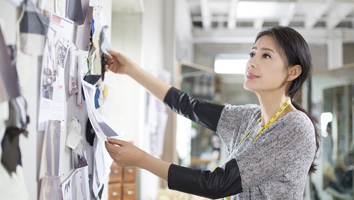 A lady tailor is looking at her design board; image used for HSBC Wealth Management page.
