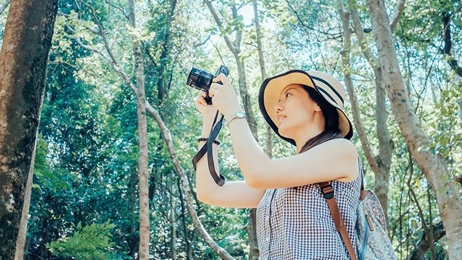 A woman taking pictures in the woods; image used for HSBC Horizons.