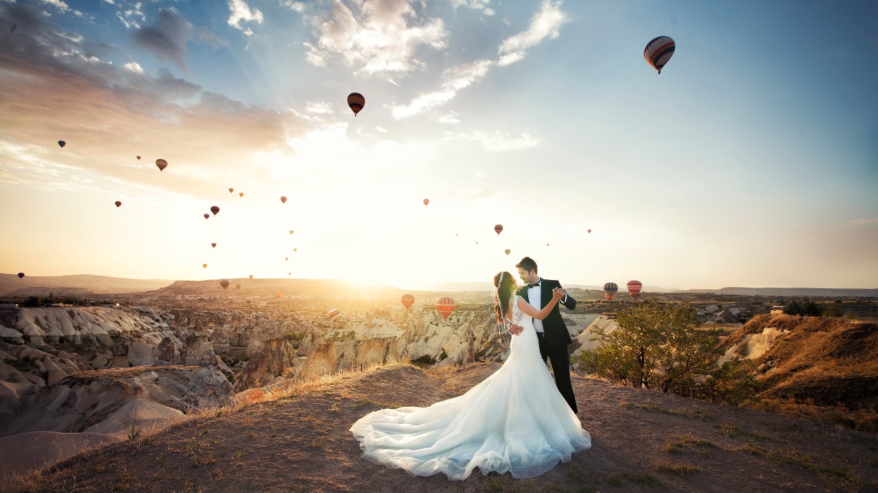 A couple is wearing their wedding dress and dancing in the mountain, image used for "Destination wedding planning" article