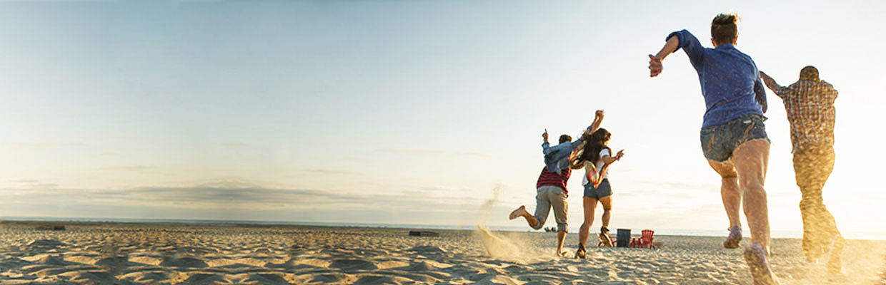 Back view of four people running on a sandy beach; image used for HSBC Fee Waiver page