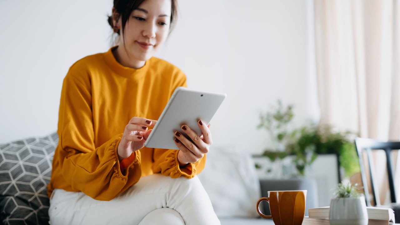 The lady sitting on the sofa looking at tablet.