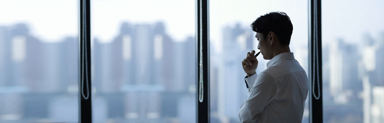 Young businessman holding a pen standing in office; image used for the HSBC Money Worries page