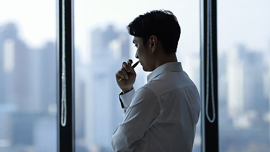 Young businessman holding a pen standing in office; image used for the HSBC Money Worries page