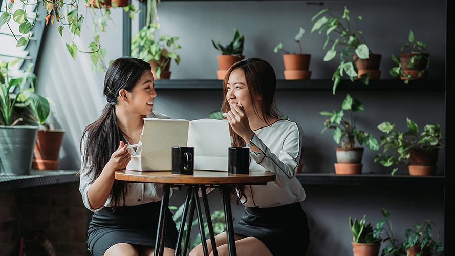 A woman is chatting with her friend in a cafe; image used for "Habits for financial wellbeing" article