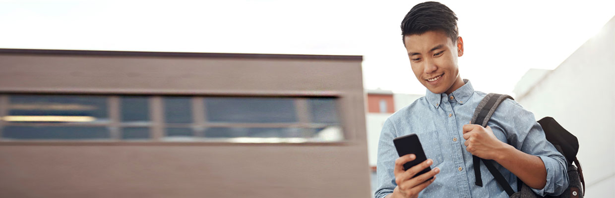 一個快樂的年輕學生，在城市中使用他的智能手機；圖片使用於滙豐 x 轉數快頁面。