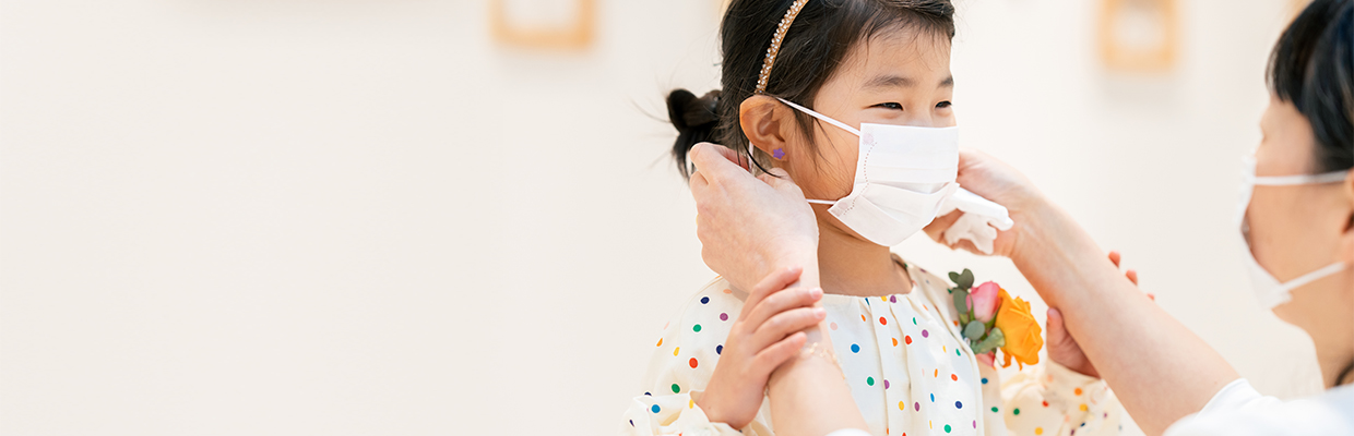 Adult putting mask on daughter face; image used for 「Are you protected enough?」 page.