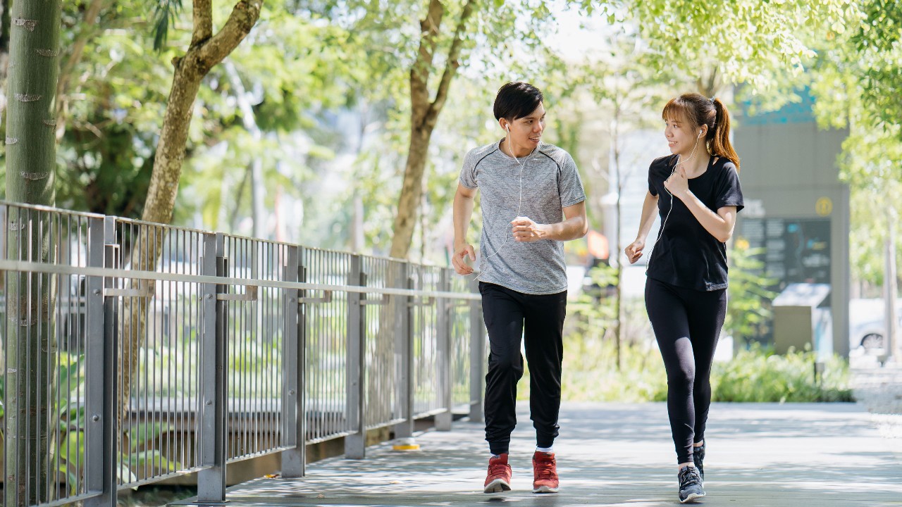 一对夫妇互相看着对方，穿着运动服跑步。