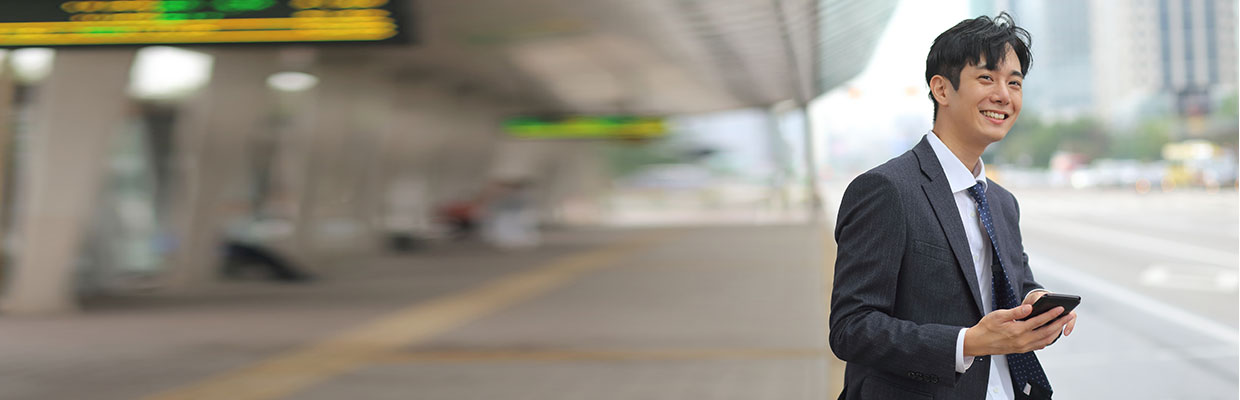 A young businessman is smiling and using his mobile; image used for HSBC stock trading