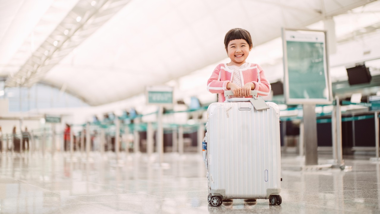 A girl smiles when she is holding her luggage; image used for HSBC structured products
