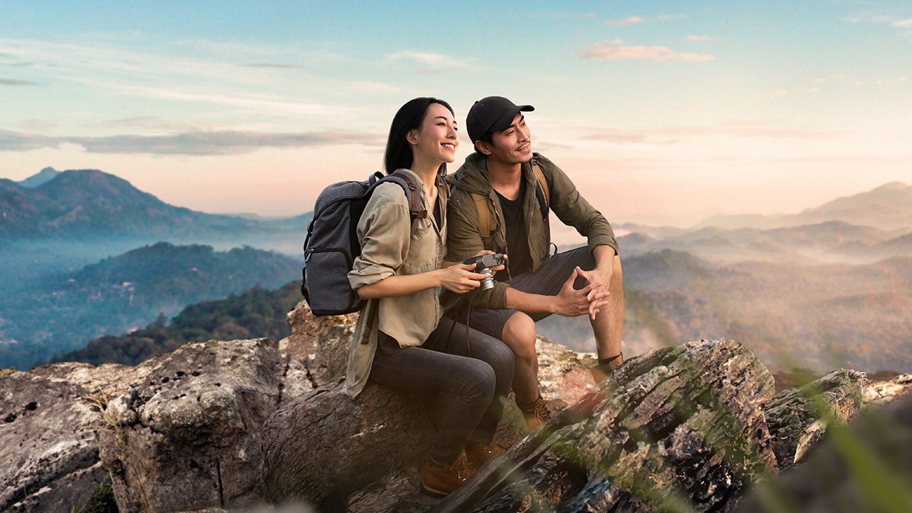 hiking couple sitting on the top of a hill