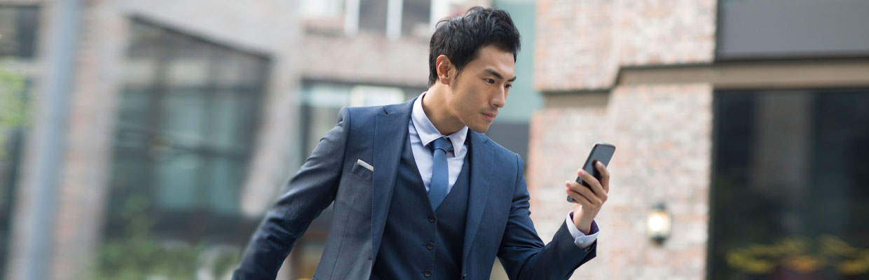 Businessman use his smartphone to read the latest news; image used for "Time Saver" article.