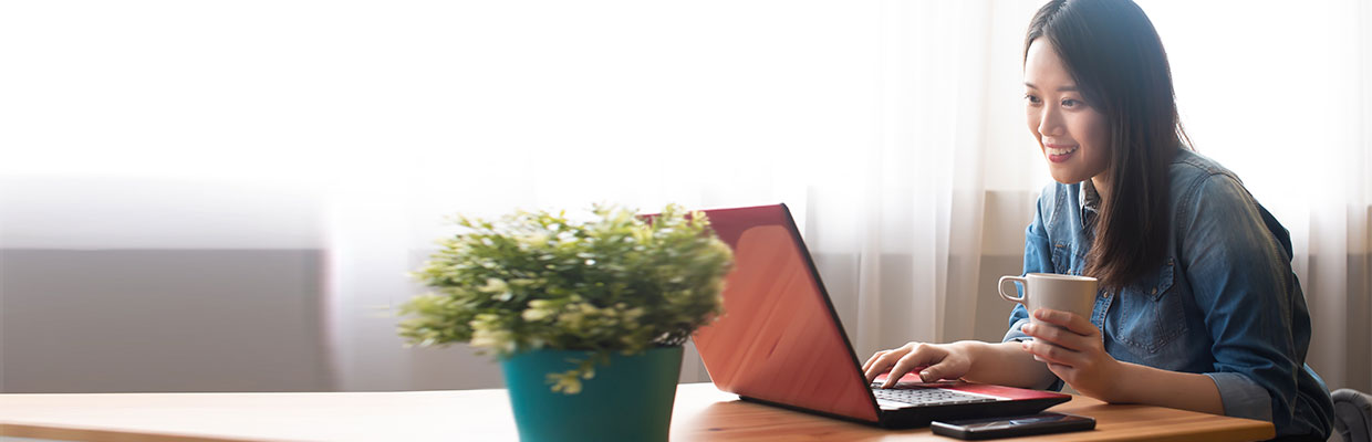 A lady is happily using notebook; the image used for online banking.