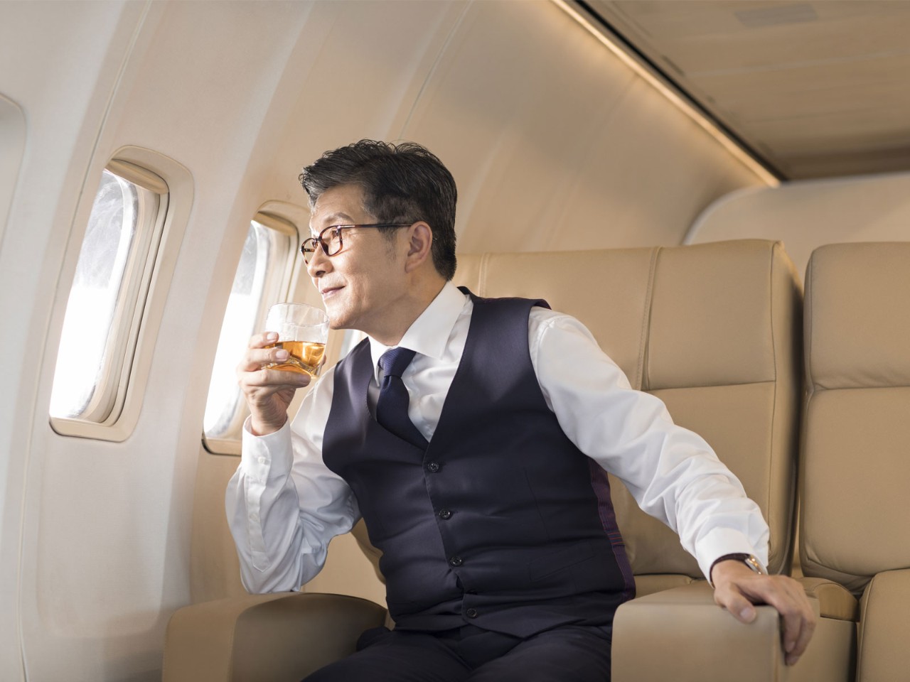 A businessman is looking outside of the plane window