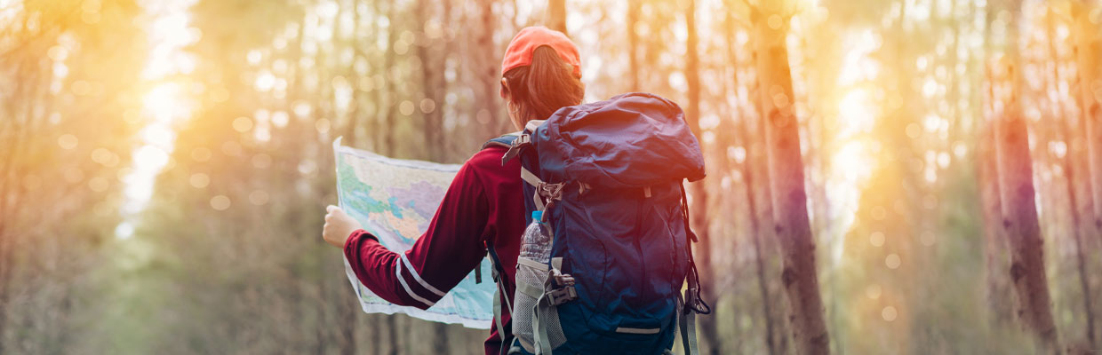 A girl is looking at a map in the wild; image used for Investments Article Page.