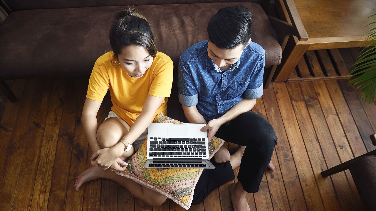 Two people look at the laptop happily