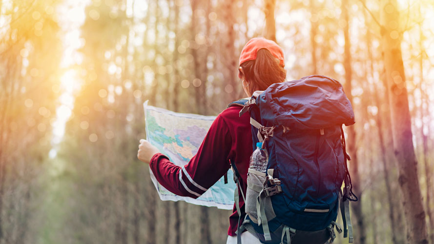 A girl is looking at a map in the wild; image used for Investments Article Page.