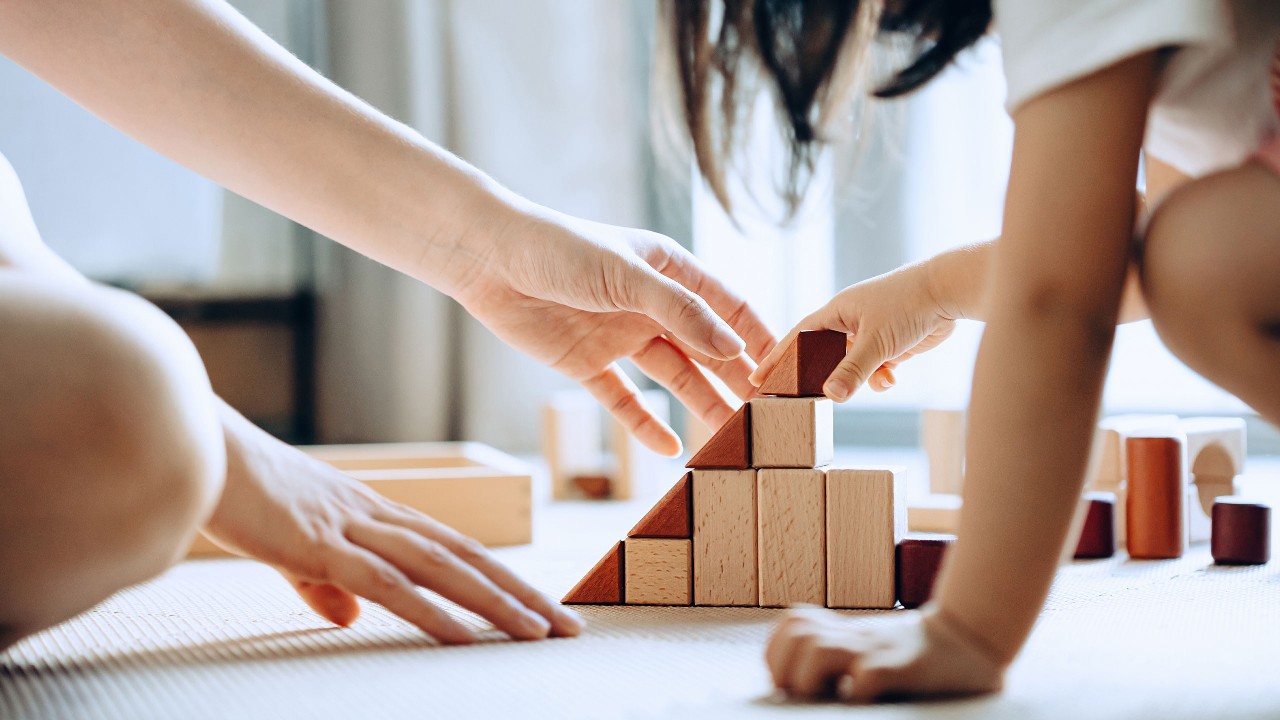 mother and daughter playing building blocks on the floor