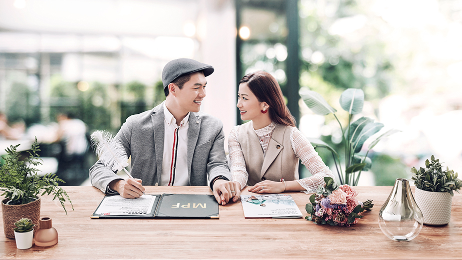 A pair sweethearts is signing document on the table, image used for latest hsbc mpf offer.