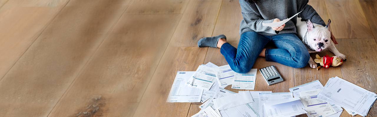 A lady is checking her bills while holding her puppy; image used for HSBC Bill Payments Merchant List