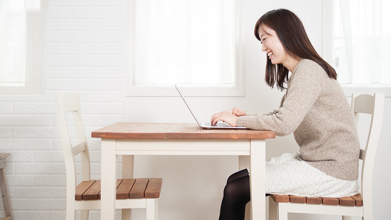 A smiling woman looking at her laptop; image used for HSBC’s e-Cheque services.